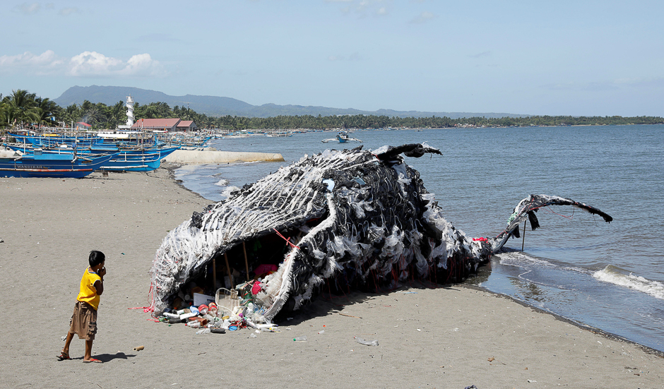 A boy looks at a whale shaped art installation that is made of plastic and trash made by environmental activist group Greenpeace Philippines, lying along the shore in Naic, Cavite, in the Philippines. PHOTO: REUTERS