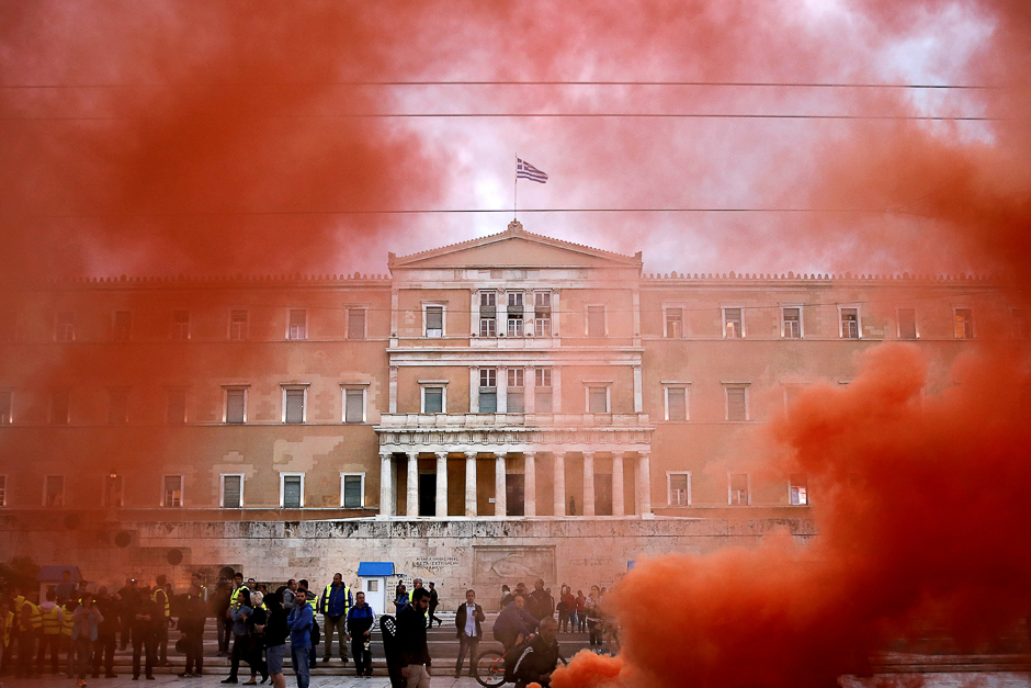 The parliament building is seen through flare smoke during a demonstration of uniformed officers marking a 24-hour general strike against the latest round of austerity in Athens, Greece. PHOTO: REUTERS