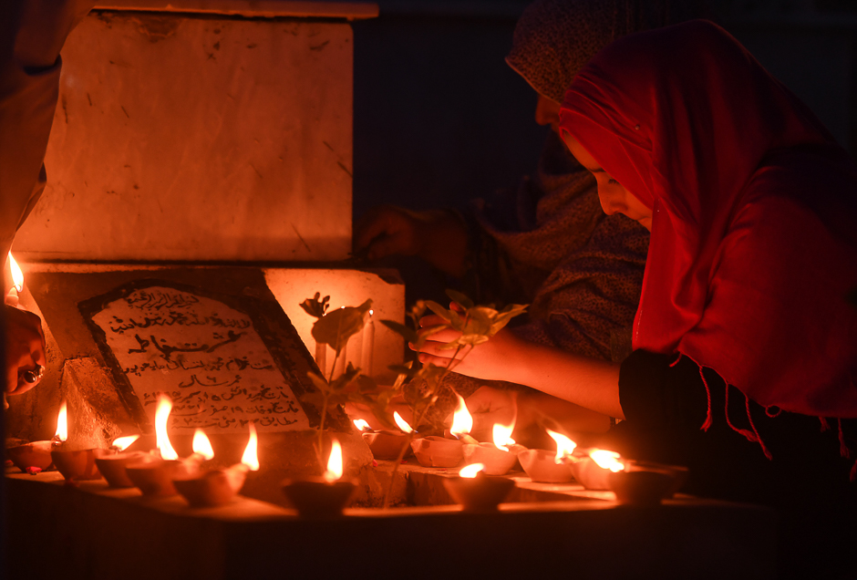 Pakistani Muslim women read Quran beside the grave of a relative to mark Shab-e-Barat at a graveyard in Karachi. PHOTO: AFP