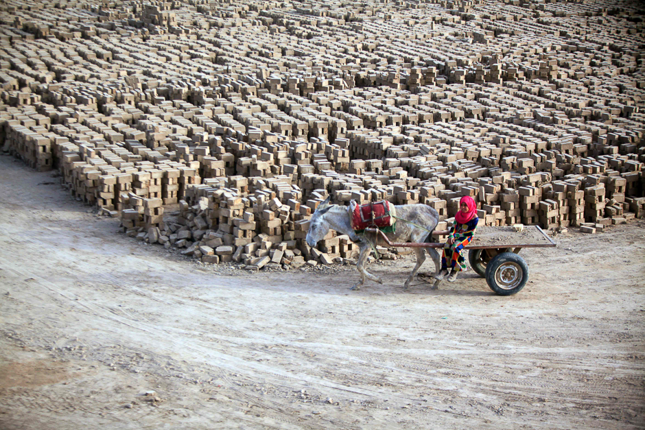 An Iraqi girl rides a donkey-drawn cart at a brick factory near the central Iraqi shrine city of Najaf. PHOTO: AFP