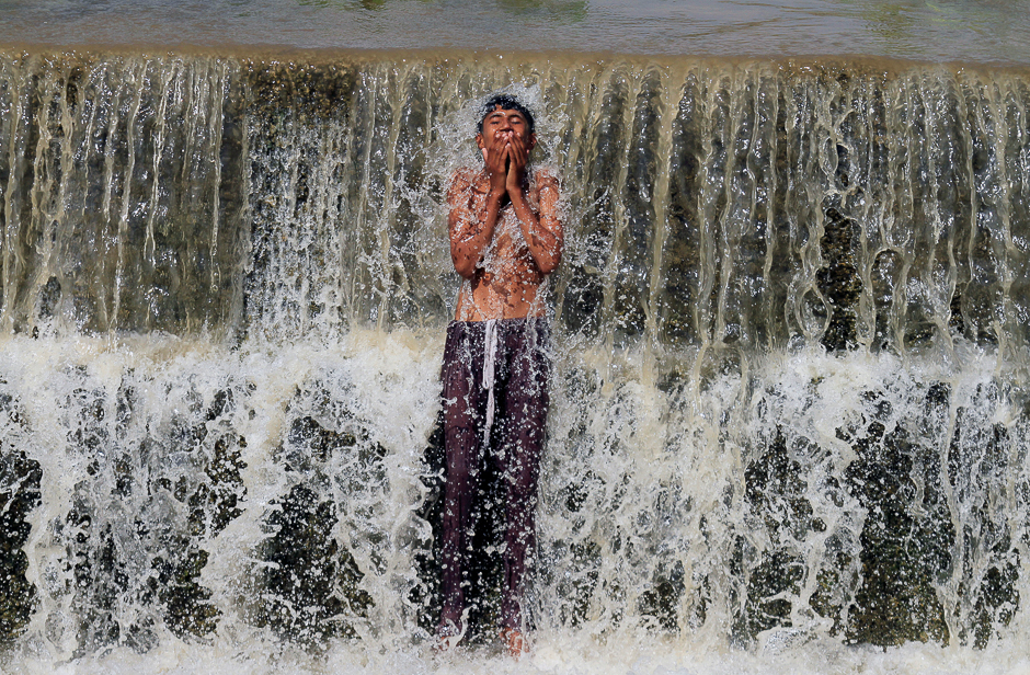 A boy bathes in a stream to cool off from the heat on a hot summer day in Swabi, Pakistan. PHOTO: REUTERS