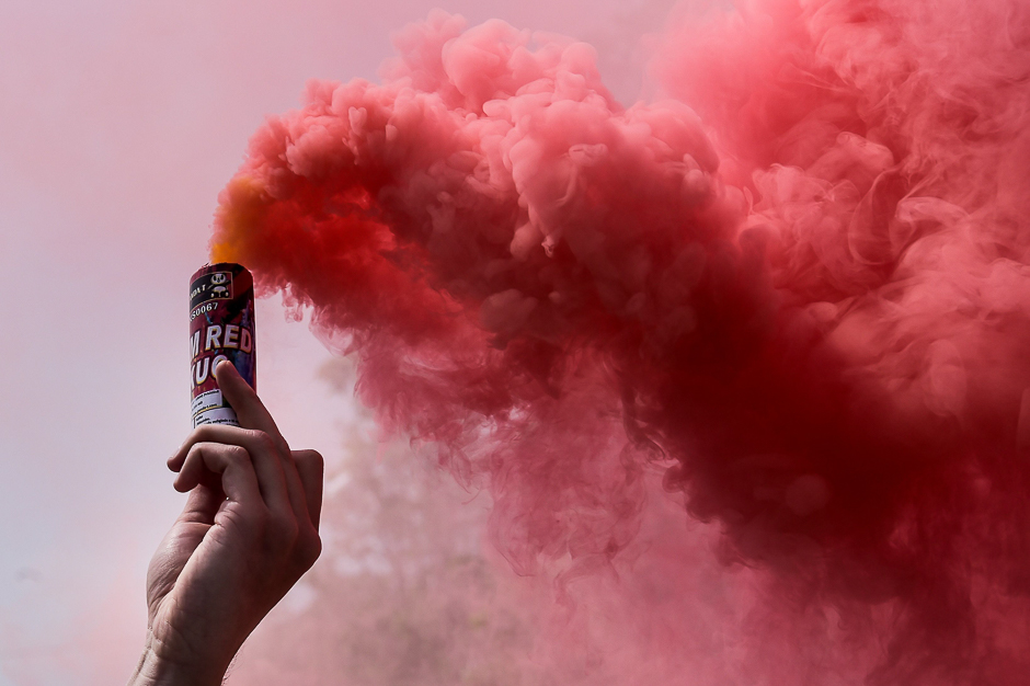 A man holds a flare during a May Day rally in Pristina. PHOTO: AFP