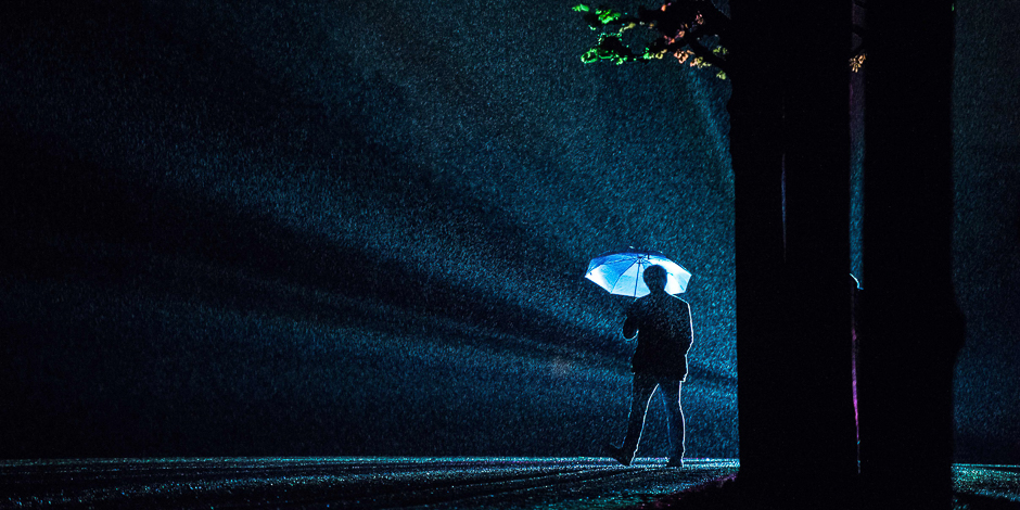 A visitor silhouettes against rays of light of the installation 