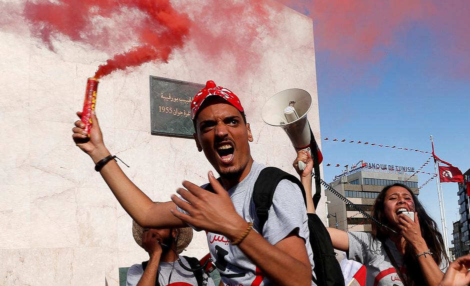 Demonstrators hold flares during a demonstration against a bill that would protect those accused of corruption from prosecution on Habib Bourguiba Avenue in Tunis, Tunisia. PHOTO: REUTERS