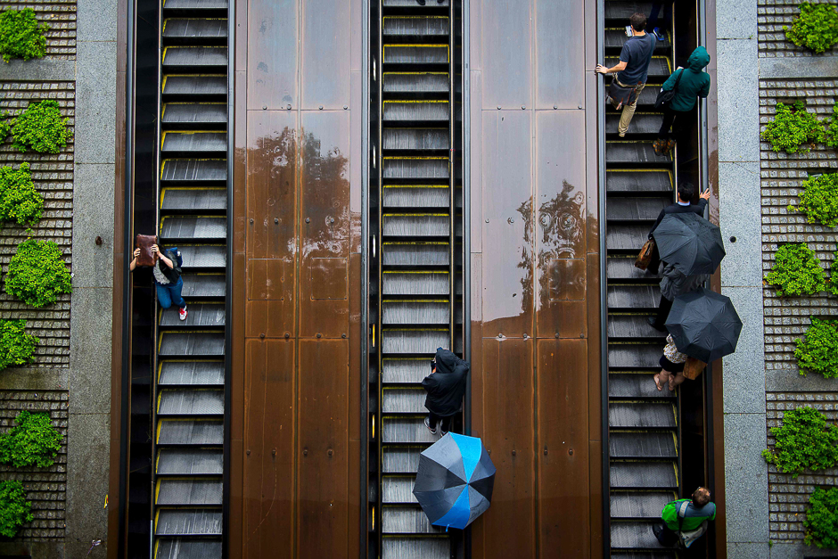 People are seen at the gDupont Circle Metro Station holding umbrellas in the rain in Washington, DC. PHOTO: AFP