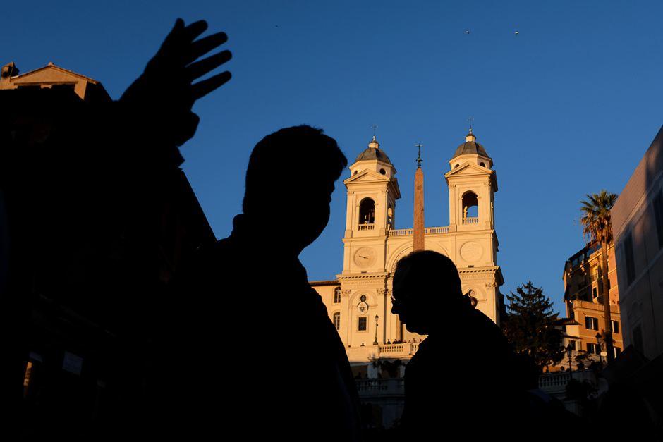 People are sihouetted at sunset with the Trinita dei Monti church in the background on May 3, 2017 in Rome. PHOTO: AFP