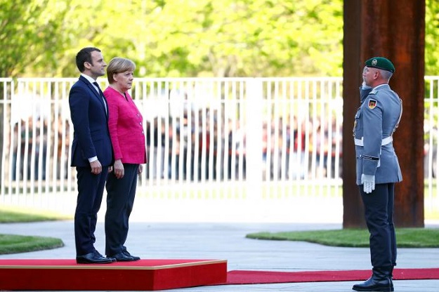German Chancellor Angela Merkel and French President Emmanuel Macron listen to national anthems during a ceremony at the Chancellery in Berlin, Germany, May 15, 2017. PHOTO: REUTERS