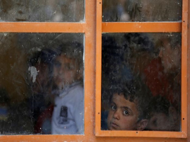 Schoolchildren are seen through the window as they attend their class at school in eastern Mosul, Iraq.  PHOTO: REUTERS