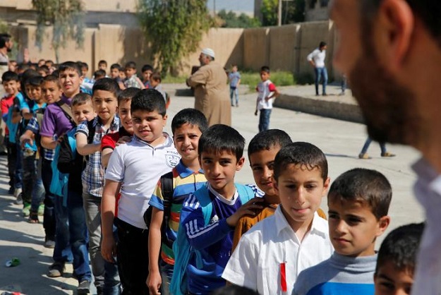 Schoolchildren stand in a line to attend their class at school in eastern Mosul, Iraq. PHOTO: REUTERS