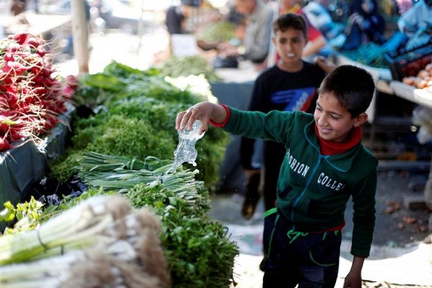 Ammar, an Iraqi child, sells vegetables and fruits in a market in eastern Mosul, Iraq. PHOTO: REUTERS