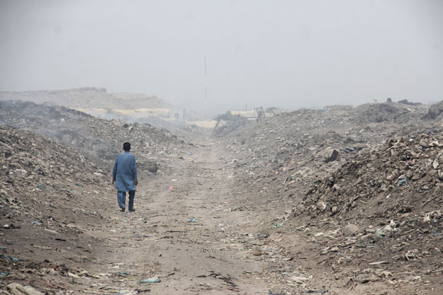 The path to the school involves children making their way through piles of burning garbage. PHOTO: AYESHA MIR/EXPRESS