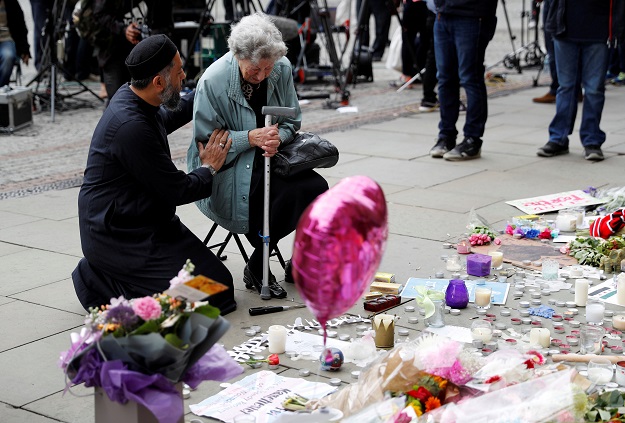 A Jewish woman named Renee Rachel Black and a Muslim man named Sadiq Patel react next to floral tributes in St Ann's Square in Manchester, Britain. PHOTO: REUTERS