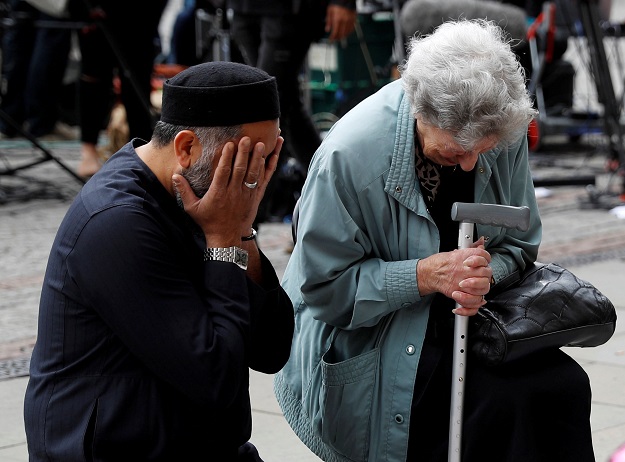 A Jewish woman named Renee Rachel Black and a Muslim man named Sadiq Patel react next to floral tributes in Albert Square in Manchester, Britain. PHOTO: REUTERS