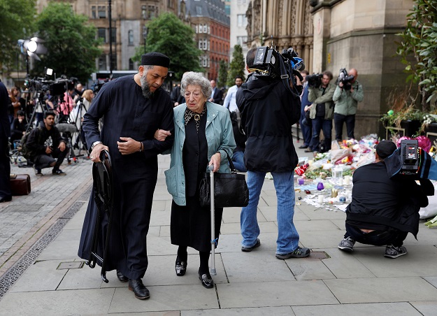A Muslim man named Sadiq Patel and a Jewish woman named Renee Rachel Black walk by floral tributes in Albert Square in Manchester, Britain. PHOTO: REUTERS