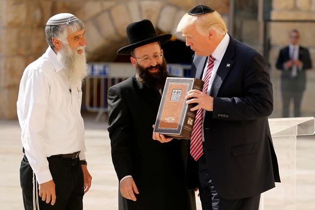 US President Donald Trump (R) receives a gift of a book of Psalms from Western Wall Heritage Foundation Director General Mordechai Elias (L) and Rabbi of the Western Wall Shmuel Rabinovitch (C) after leaving a note at the Western Wall in Jerusalem May 22, 2017.  PHOTO: REUTERS