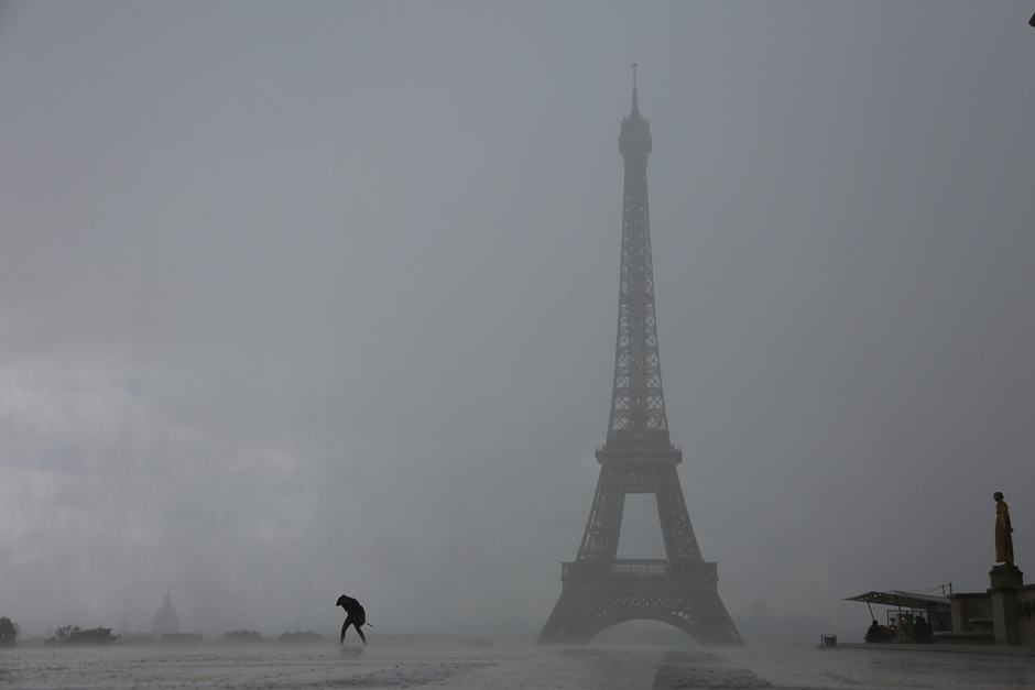 Tourists and Parisians run to protect themselves from a short heavy rain on Trocad ro square, in front of the Eiffel tower. PHOTO: AFP