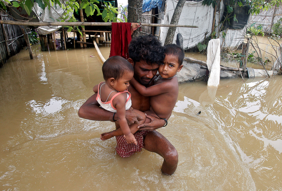 A man carries his children out of their flooded hut to move to a safer place after heavy rains, on World Environment Day, on the outskirts of Agartala, India. PHOTO: REUTERS