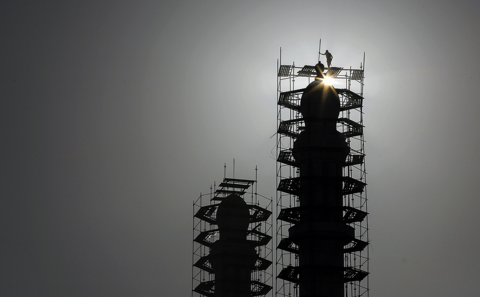 Palestinian workers perform maintenance work on the minarets on a mosque in Gaza City. PHOTO: AFP