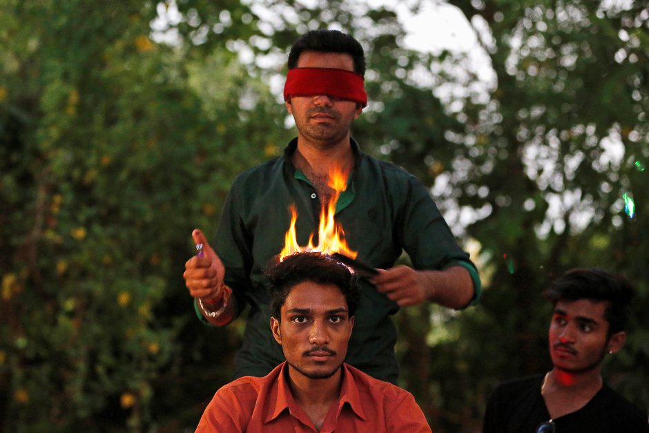 Vishnu Limbachiya, a hair artist, styles the hair of a man while wearing a blindfold at a park in Ahmedabad, India. PHOTO: REUTERS