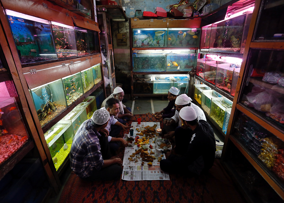 Muslims eat their Iftar (breaking fast) meals inside a shop selling fish during the holy month of Ramadan, in Mumbai, India. PHOTO: REUTERS