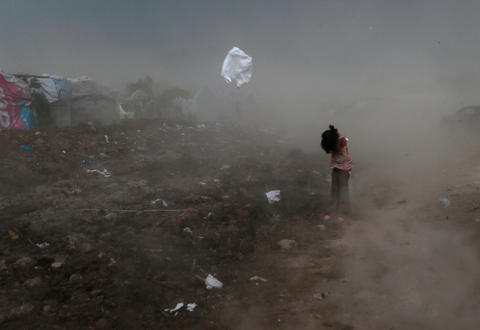 A girl protects herself from garbage and dust, raised by a gust of wind, in a slum in Islamabad, Pakistan. PHOTO: REUTERS