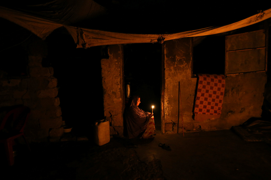 A Palestinian woman lights a candle inside her house during power cut in the southern Gaza Strip. PHOTO: REUTERS