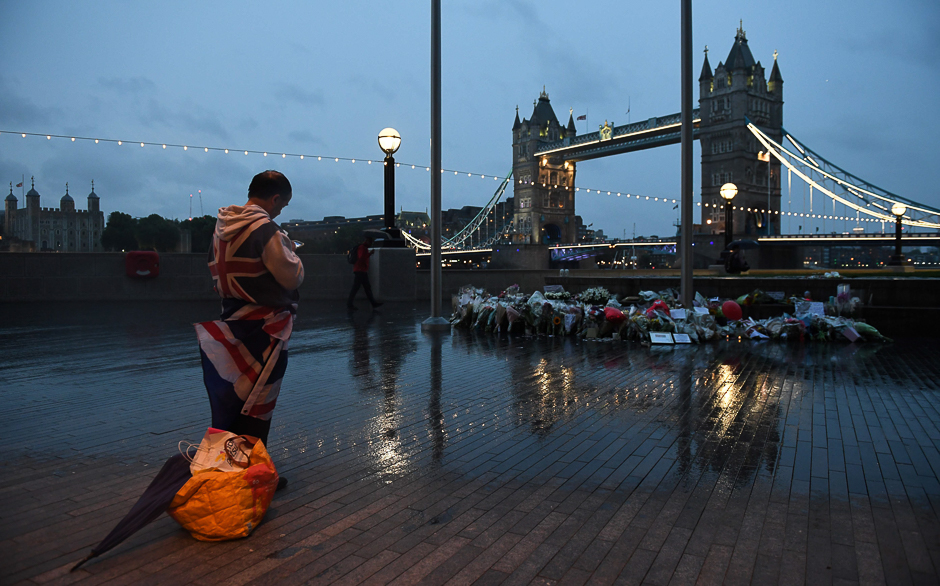 A man stands near flowers layed at Potters Fields Park in London. PHOTO: AFP