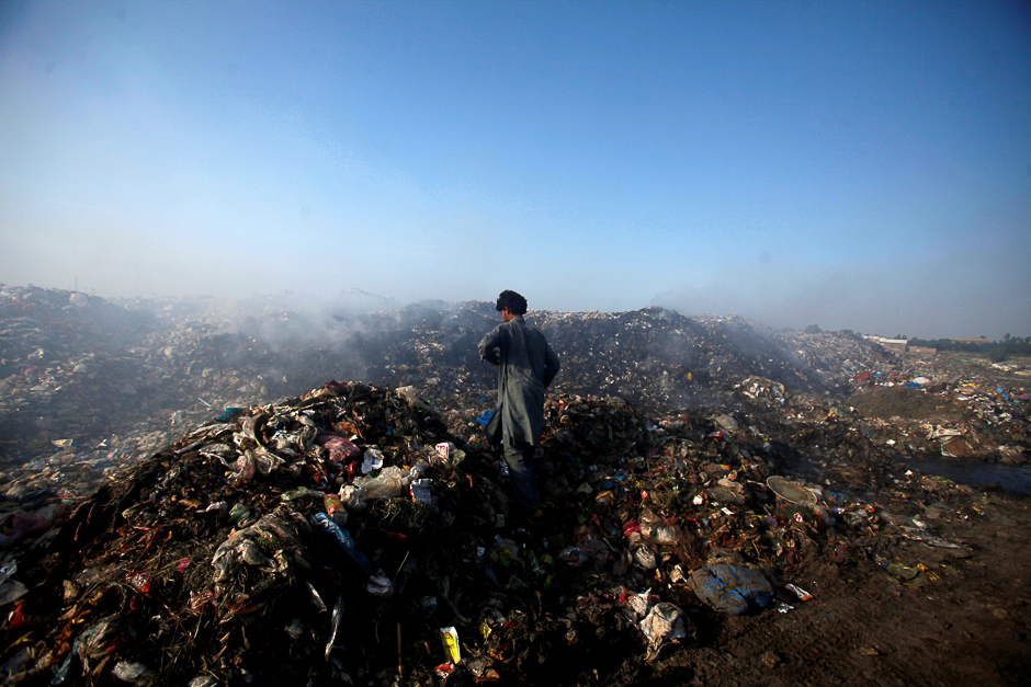A man walks through a burning garbage dump on the outskirts of Peshawar, Pakistan. PHOTO: REUTERS