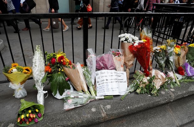 Commuters walk past flowers and messages left outside Monument Underground station next to London Bridge. PHOTO: REUTERS
