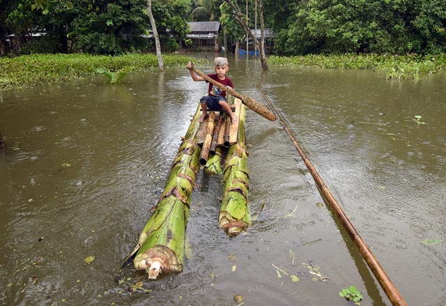 a boy rows a makeshift raft outside his submerged house in the flood affected kuthori village near kaziranga national park in nagaon district in the northeastern state of assam india july 11 2017 photo reuters