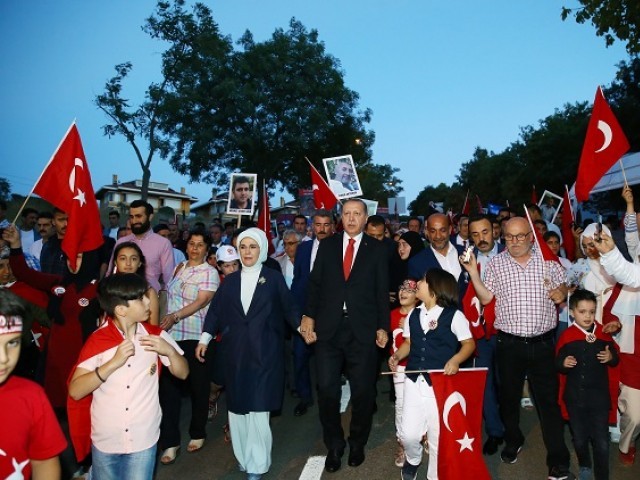 Turkish Presidential Press Service shows Turkey's President Recep Tayyip Erdogan (C) and his wife Emine Erdogan (C/L) as they walk to a ceremony site on July 15 Martyrs Bridge" (Bosphorus Bridge) in Istanbul. PHOTO: AFP