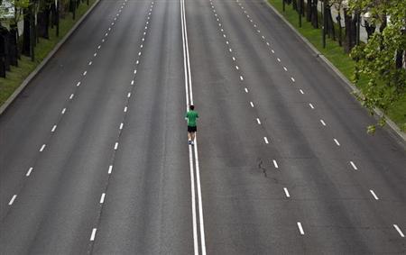 a runner warms up in the middle of an empty avenue photo reuters