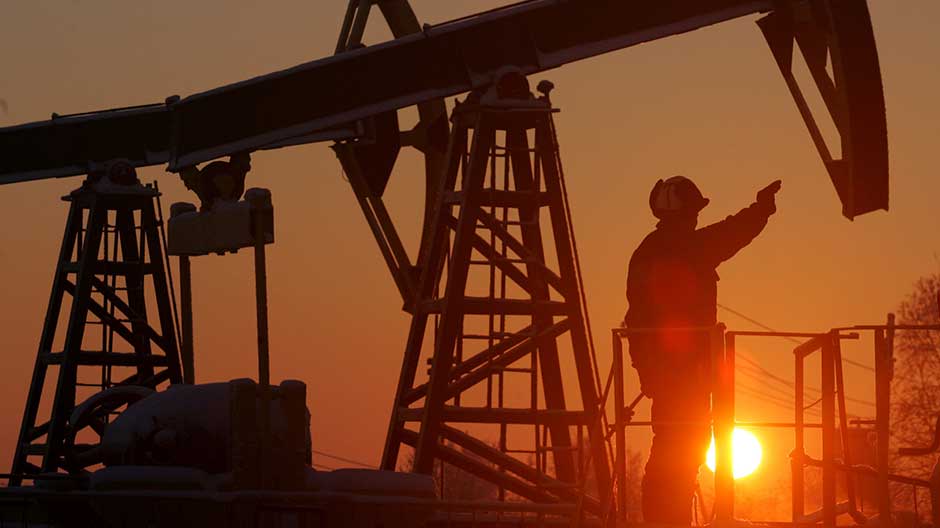 a worker stands under a derrick at a oil processing facility photo reuters