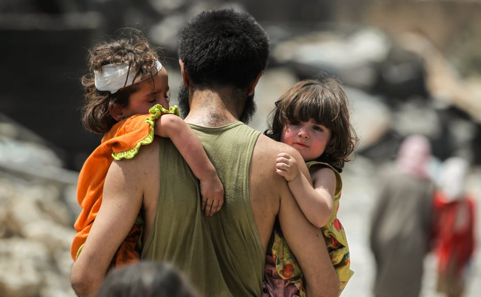 A man carries two children in his arms hile fleeing from the Old City of Mosul. PHOTO: REUTERS