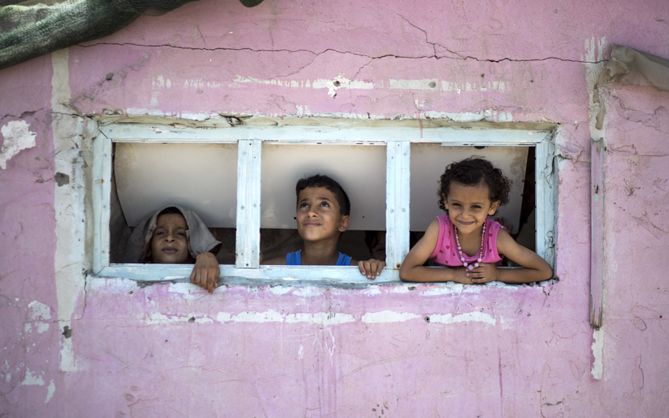 Palestinian children are seen looking outside a window during a heatwave at al-Shati refugee camp in Gaza City. PHOTO: AFP