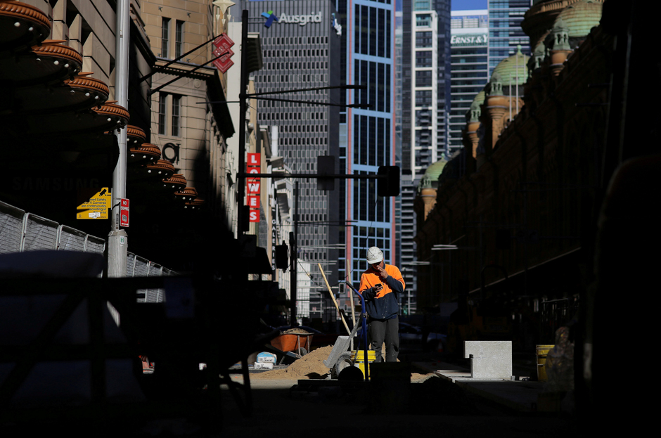 A construction worker smokes a cigarette as he looks at his mobile phone on a worksite in Sydney, Australia. PHOTO: REUTERS