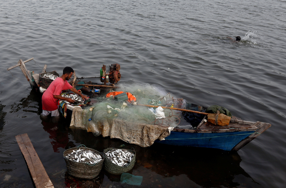 A fisherman unloads baskets of fish from a boat after he returned from a day catch, along China Creek area of Karachi, Pakistan. PHOTO: REUTERS