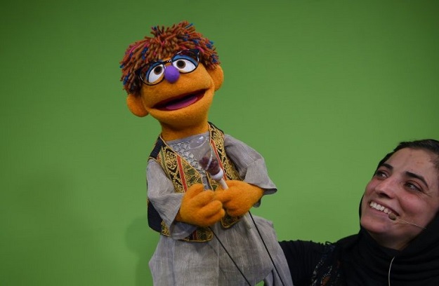 Afghan puppeteers Seema Sultani (R) holds new Sesame Street Muppet 'Zeerak' during a recording at a television studio in Kabul. PHOTO: AFP