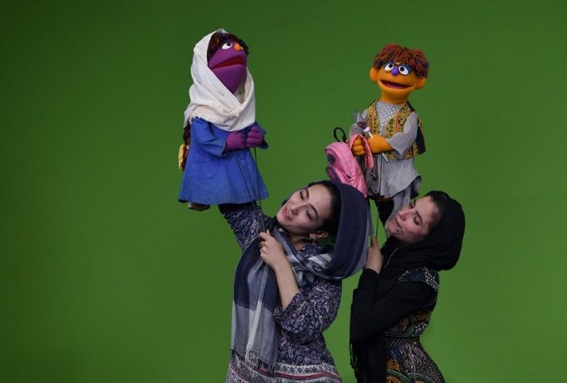 Afghan puppeteers Seema Sultani (R) holds new Sesame Street Muppet 'Zeerak' as she performs with colleague Mansoora Shirzad, holding Muppet 'Zari', during a recording at a television studio in Kabul. PHOTO: AFP
