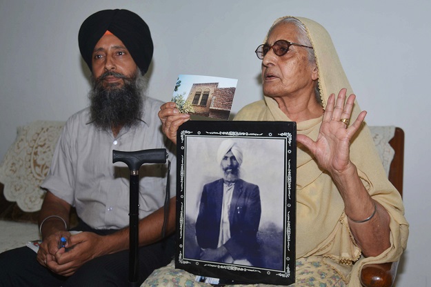 Sushwant Kaur, 78, shows a photograph of her late father Sulkhan Singh, with her son Jaswinder Singh (L) in Amritsar, India. PHOTO: AFP