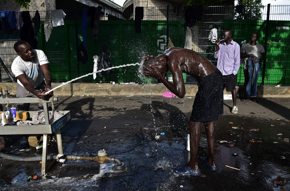 Migrants bathe on the pavement at Porte de la Chapelle, Paris, France. PHOTO: AFP