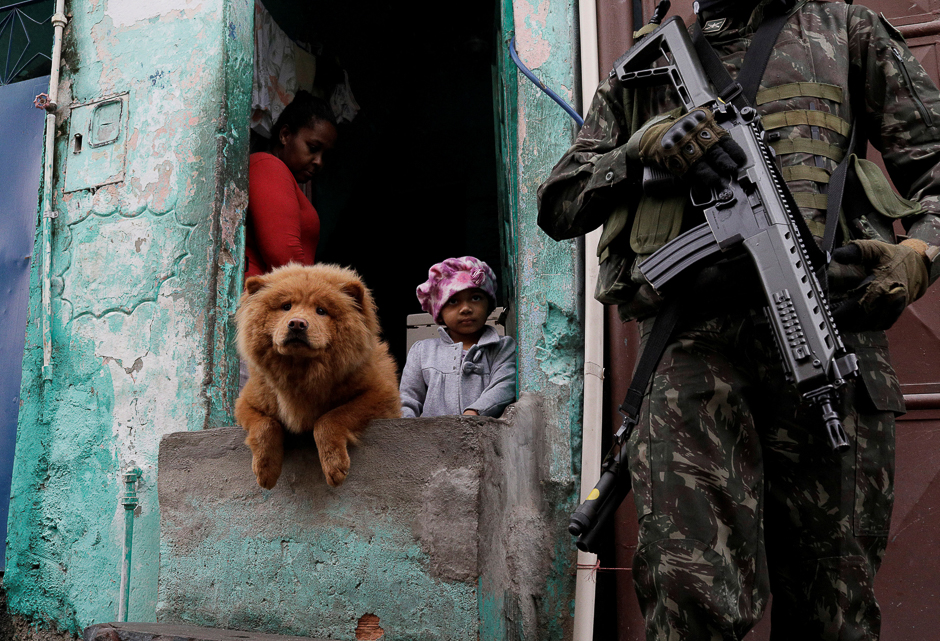 Armed Forces members patrol, as residents watch, during an operation against organised crime in Manguinhos slum complex in Rio de Janeiro, Brazil. PHOTO: REUTERS