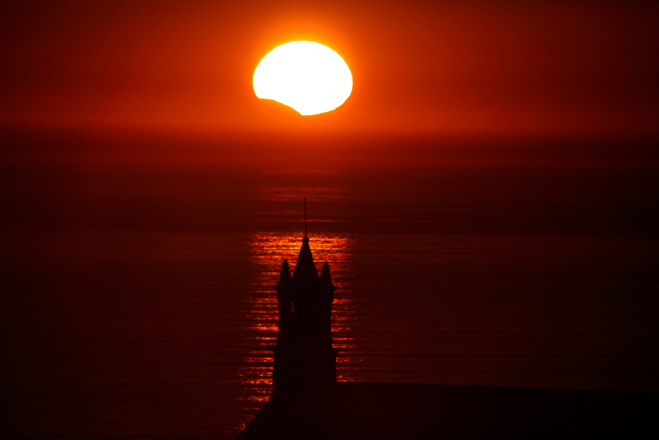 The Saint-They Chapel is seen in silhouette at sunset during a partial solar eclipse, as the moon passes in front of the sun, seen at the Pointe du Van, in Brittany, France. PHOTO: REUTERS
