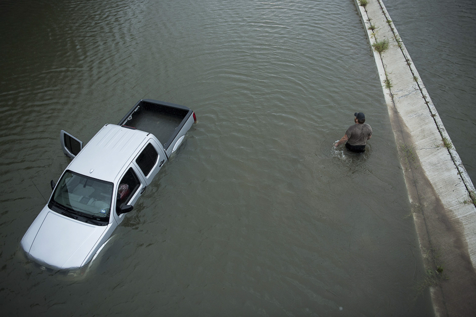 A truck driver walks past an abandoned truck while checking the depth of an underpass during the aftermath of Hurricane Harvey August 28, 2017 in Houston, Texas. PHOTO: AFP