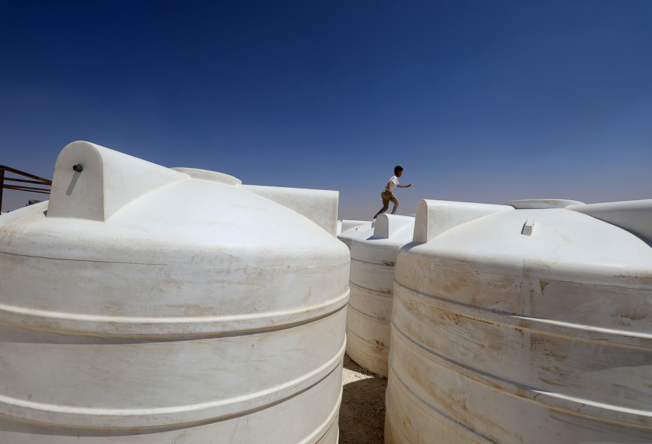 A displaced child from the Islamic State (IS) group's Syrian stronghold of Raqa, runs along to top of water containers at a camp in Ain Issa. PHOTO: AFP