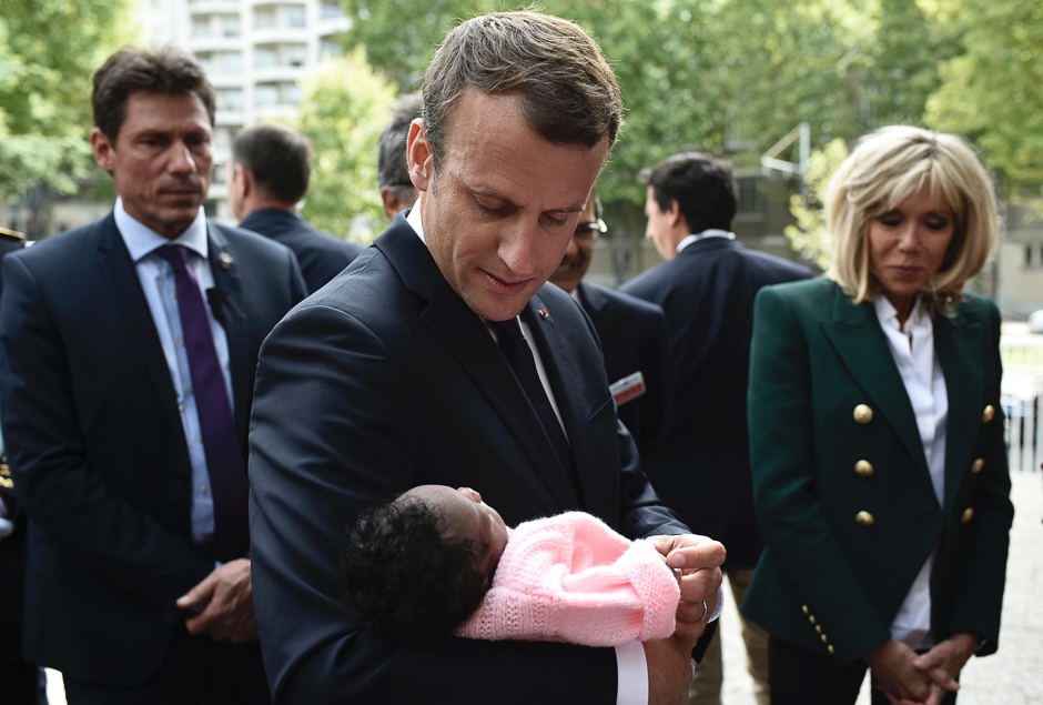 French President Emmanuel Macron (C), flanked by his wife Brigitte Macron (R), holds a newborn as he visits the Robert Debre pediatric hospital in Paris. PHOTO: AFP