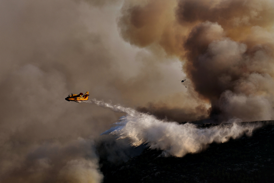 A Canadair firefighting airplane drops water above a fire at sunset, east of Athens. PHOTO: AFP