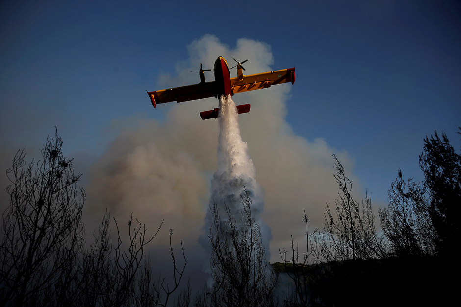 A firefighting airplane makes a water drop as a wildfire burns near the village of Metochi, north of Athens, Greece. PHOTO: REUTERS