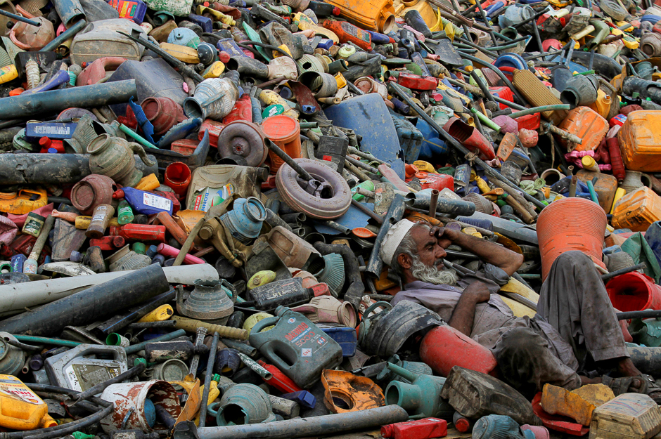 A labourer rests over a pile of recyclables at a yard in Peshawar, Pakistan. PHOTO: REUTERS