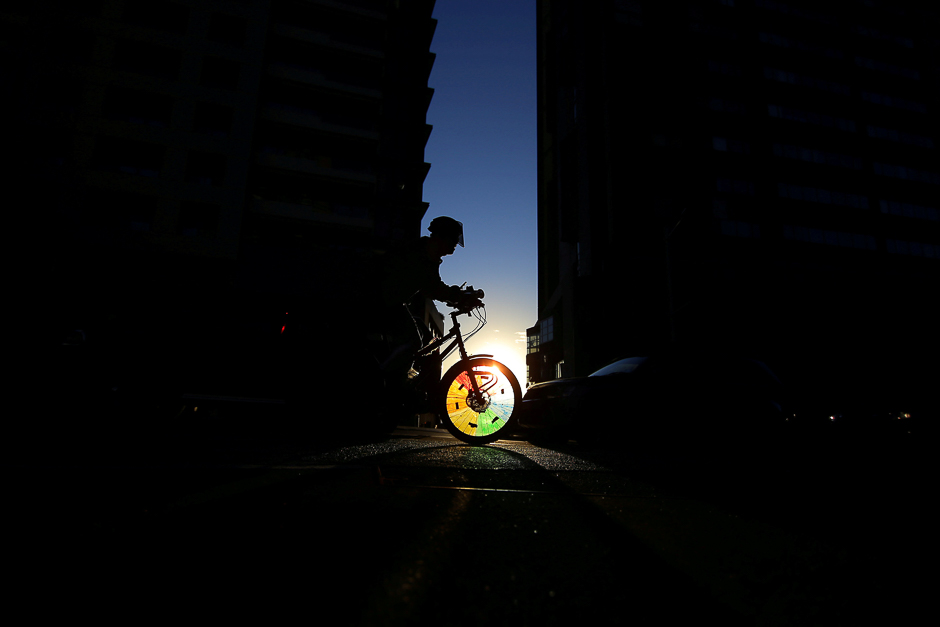 A cyclist rides into a shaft of light between two buildings in Sydney's business district, Australia. PHOTO: REUTERS